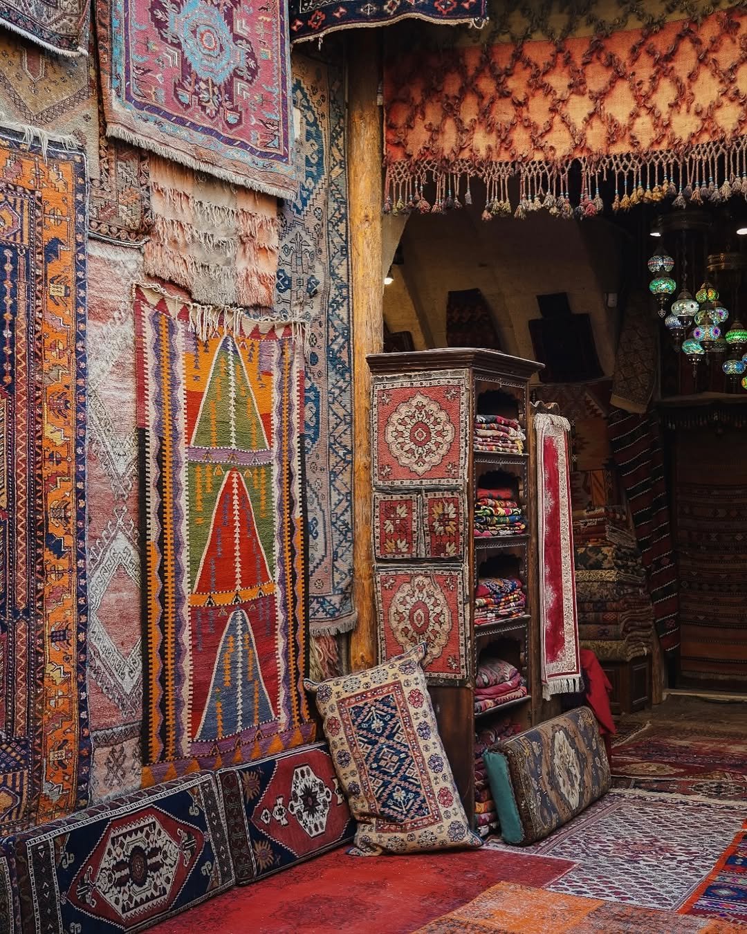 Hand-knotted Turkish rugs stacked and hung along the walls of a Sultanahmet rug shop