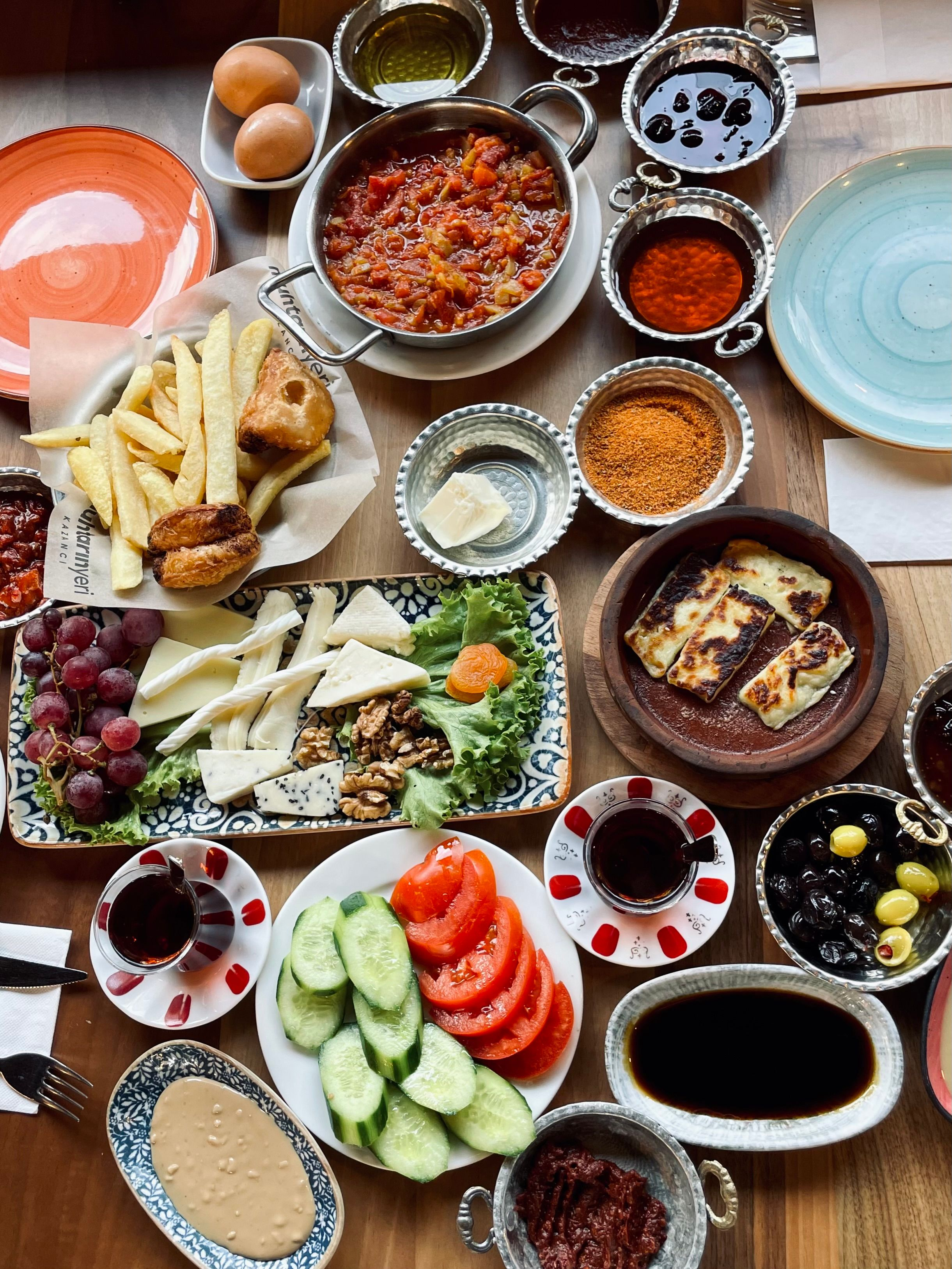 A full Turkish breakfast spread of cheeses, eggs, olives, jams, and çay laid across a table